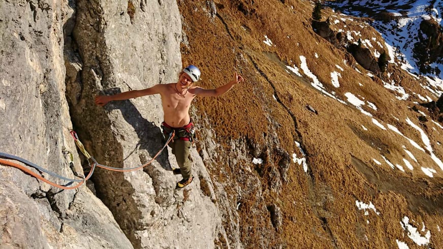 Bergführer Fabian Bendlin mit weißem Helm klettert oberkörperfrei an steiler Kalksteinwand.