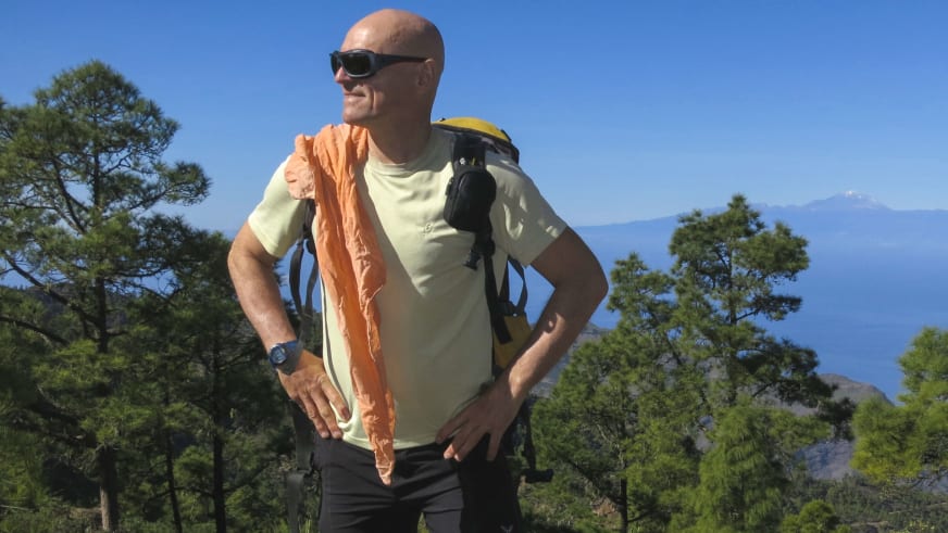 Bergwanderführer Reinald Zölch steht mit Rucksack vor mediterraner Hügellandschaft mit Meer im Hintergrund.