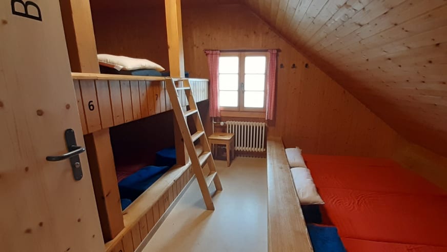 Mehrbettzimmer Badus der Vermigelhütte mit Etagenbett, Holzverkleidung und nummerierter Bettenaufteilung.
