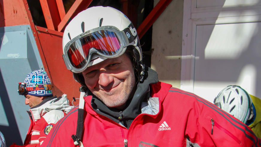 Mit weißem Skihelm und rot verspiegelter Skibrille lächelt Bergführer Franz Hölzl in roter Adidas-Skijacke in die Kamera.