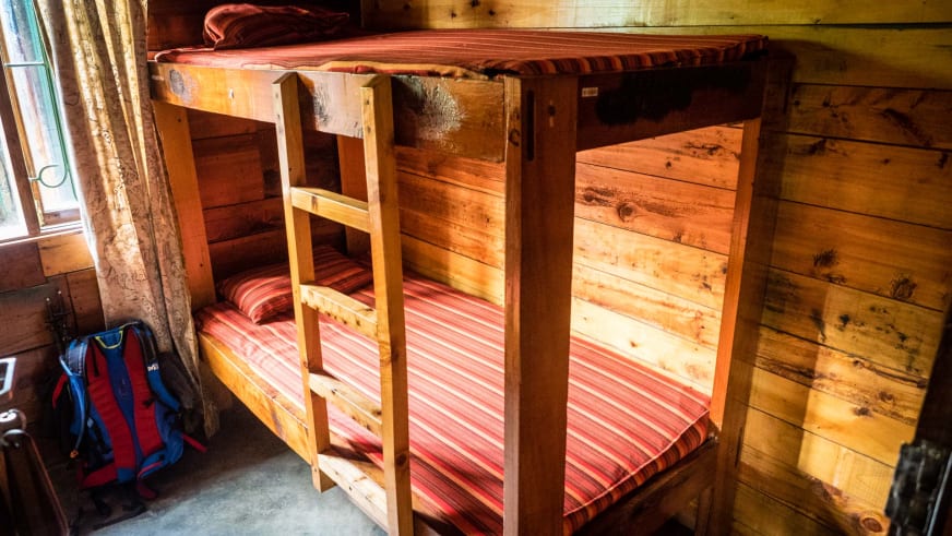 Innenansicht eines rustikalen Schlafraums mit Holz-Etagenbett in der Miriakamba Hütte am Mount Meru.