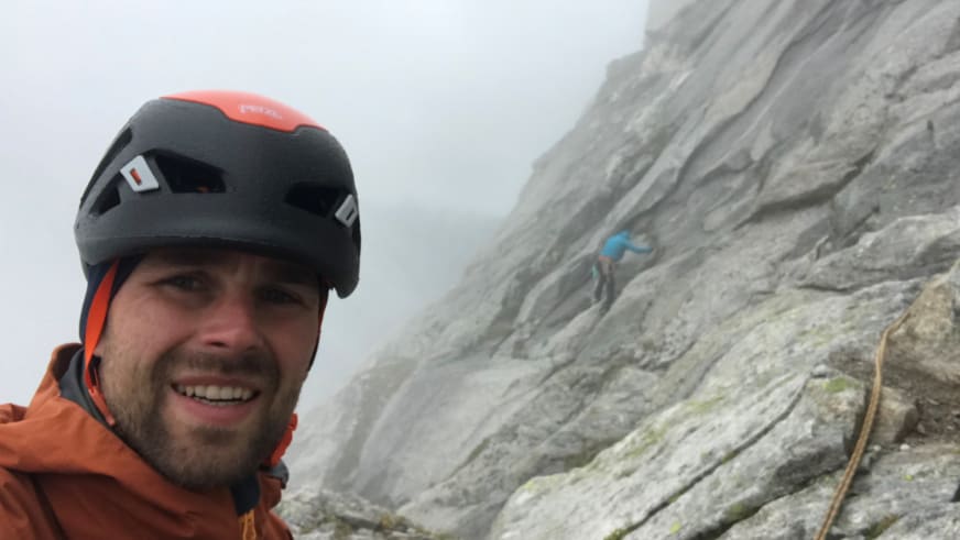 Bergwanderführer Benjamin Mäder macht Selfie mit schwarzem Helm und oranger Jacke, oranges Kletterseil sichtbar.