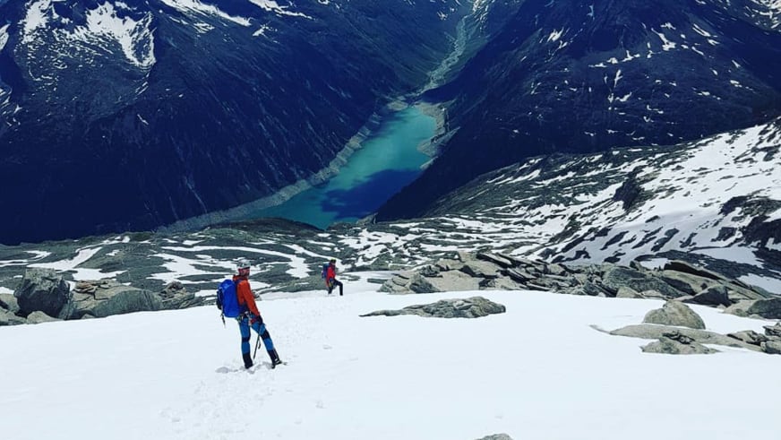 Zwei Personen mit Stöcken wandern auf Firnfeld aufwärts, Bergwanderführer Benjamin Mäder führt die Tour.