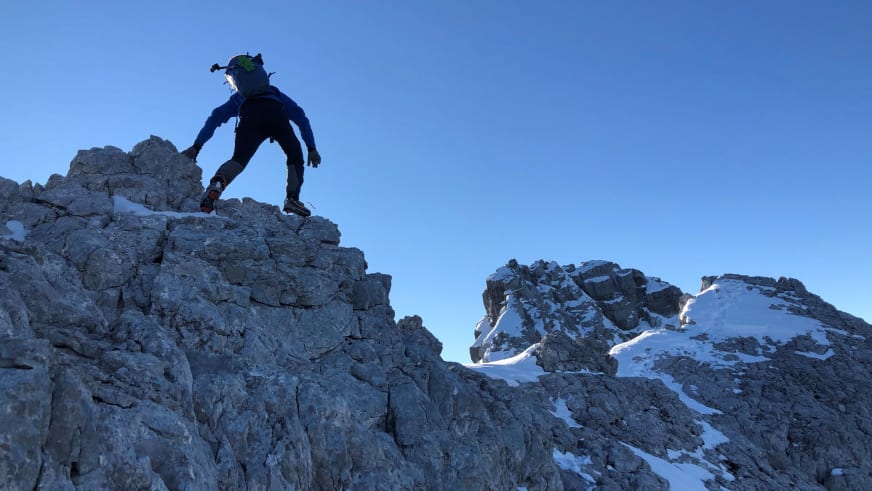 Benjamin Mäder klettert in dunkler Winterkleidung mit Helm an grauer Kalksteinwand, Bergwanderführer in steiler Position.