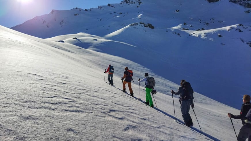 Auf einer Skitour führt Bergführer Markus Arzberger eine Gruppe von sechs Personen einen verschneiten Berghang aufwärts.