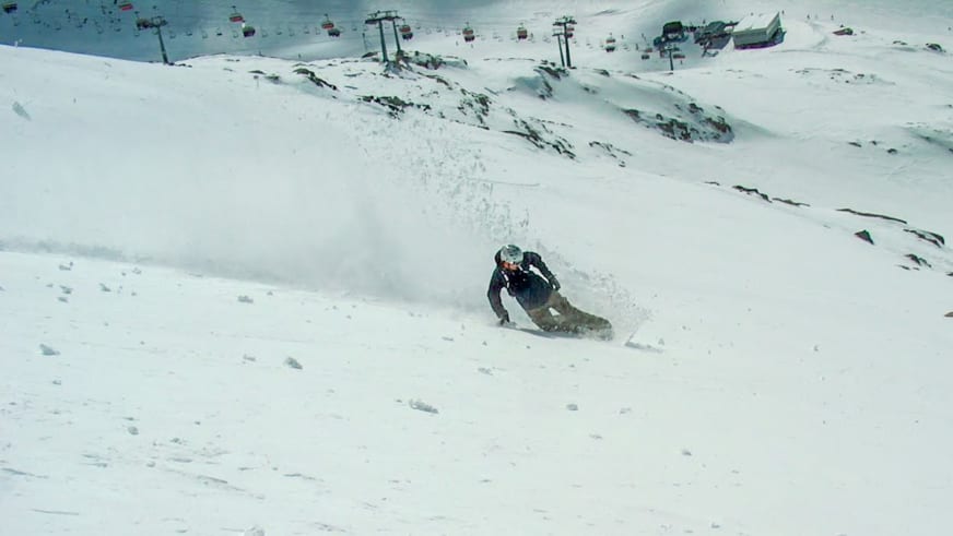 Auf den Pisten eines Skigebiets fährt Bergführer Markus Arzberger in dunkler Winterkleidung einen verschneiten Hang hinab.