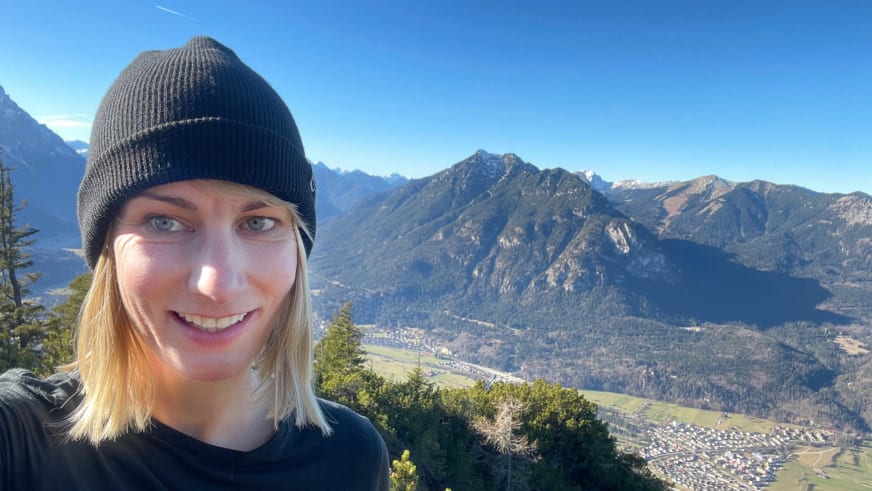 Mit grauer Wollmütze lächelt Bergwanderführerin Stefanie Erdmann vor Berglandschaft in die Kamera.