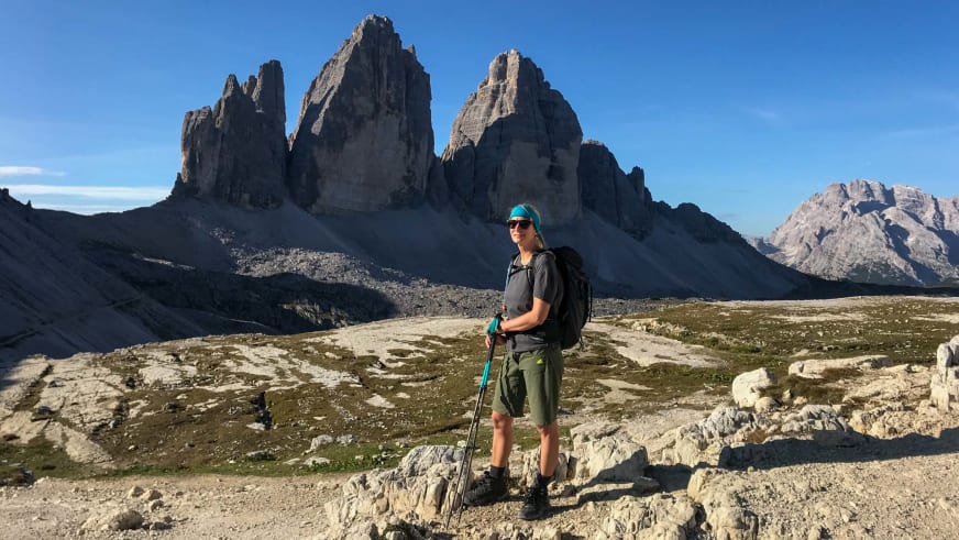Vor der Kulisse der drei Zinnen steht Bergwanderführerin Stefanie Erdmann mit Wanderstöcken auf Plateau.