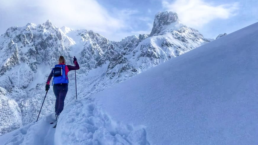 Winterwanderung: Bergwanderführerin Alina Elisabeth Leitinger steigt mit Wanderstöcken durch tiefen Schnee aufwärts.
