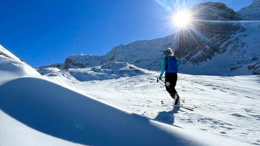 Bergwanderführerin Alina Elisabeth Leitinger fährt in blauer Jacke auf Tourenski einen steilen, verschneiten Hang hinab.