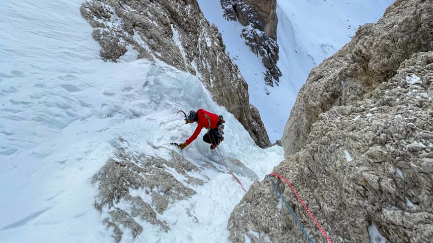 Bergführer Lukas Höllrigl klettert mit Eisgeräten und Steigeisen an steiler Eiswand zwischen grauen Felswänden.