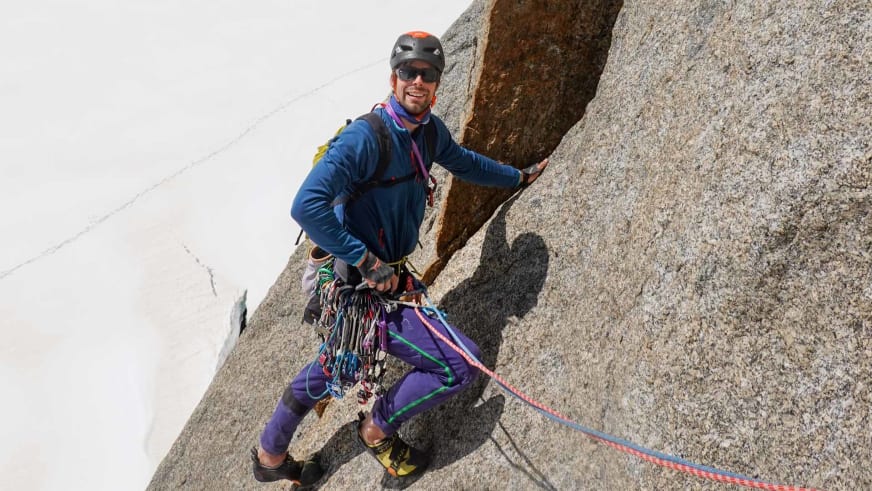 Bergführer Lukas Seedoch klettert an einer Granitwand in Chamonix mit Expressschlingen und Karabinern am Gurt.