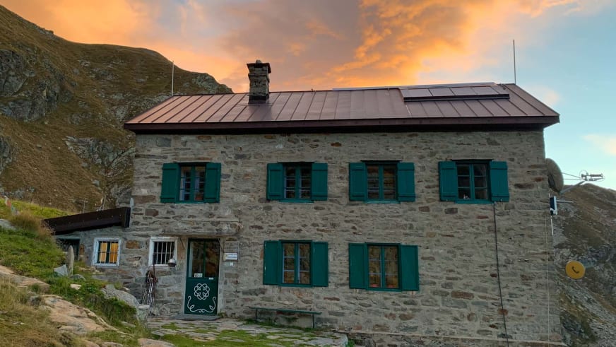 Das Rifugio Alfredo Rivetti zeigt sich als zweistöckiges Natursteingebäude mit grünen Fensterläden in den Walliser Alpen