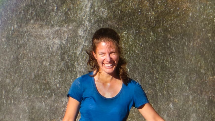 Bergwanderführerin Anna Bodenstedt mit mittellangen braunen Haaren und blauem T-Shirt lächelt direkt in die Kamera.