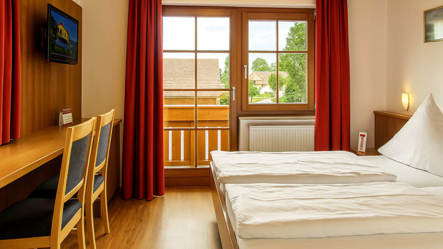 Doppelzimmer im Hotel-Garni zur Linde mit zwei Einzelbetten und Balkon mit Holzgeländer.