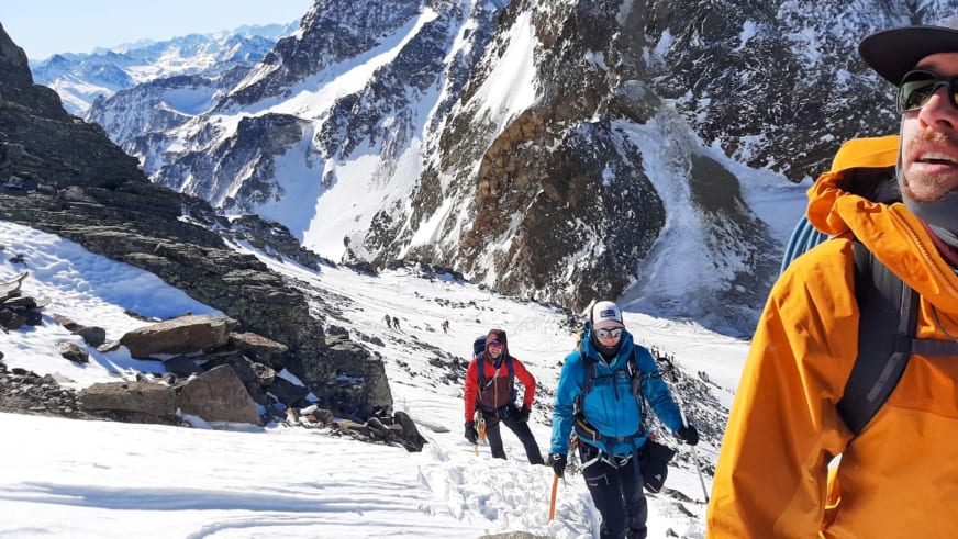 Drei Bergsteiger steigen durch verschneites Hochgebirge auf, Bergwanderführer Timo Reichert führt die Gruppe.