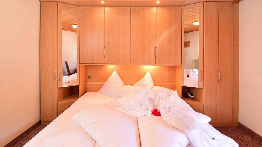 Modernes Doppelzimmer im Alpin Garni die kleine Post mit integrierter Holzschrankwand und LED-Beleuchtung.