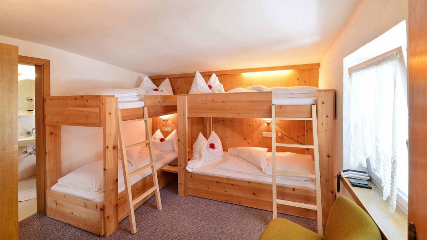 Mehrbettzimmer im Alpin Garni die kleine Post mit vier Kiefernholz-Stockbetten und weißer Bettwäsche.