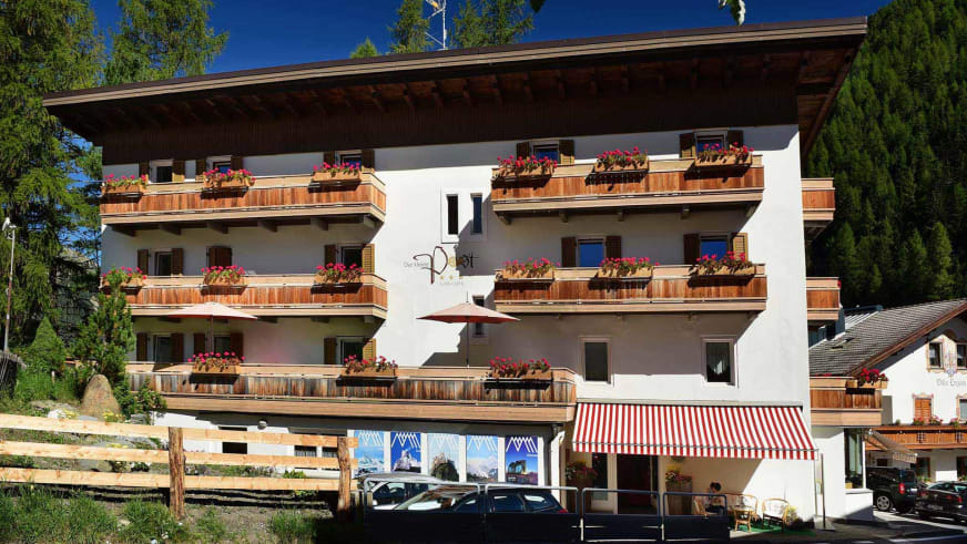 Außenansicht vom Alpin Garni die kleine Post in Sulden mit alpiner Architektur und roten Blumenkästen.