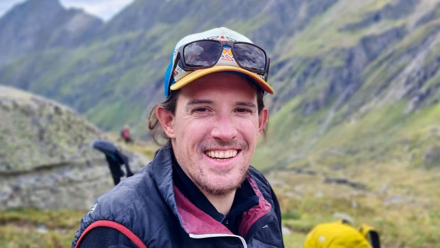 Lächelndes Portrait von Bergwanderführer Timo Reichert mit bunter Baseballkappe und blauer Outdoorjacke.