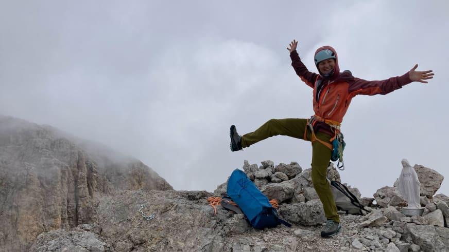 Bergführerin Elisabeth Seibt springt mit ausgebreiteten Armen auf einem Kalksteingipfel während sich Nebel über die Felswände legt.