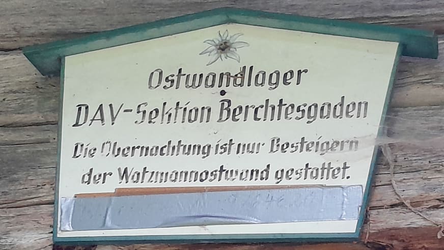 Hölzernes Hüttenschild des Ostwandlager der DAV-Sektion Berchtesgaden mit Edelweiß-Symbol.