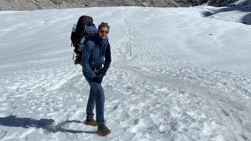 Bergführer Tim Lenz steht in blauer Jacke auf Gletscherfläche mit Routenmarkierungen im Hintergrund.