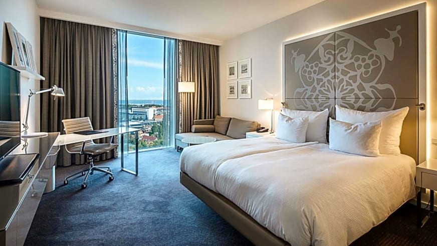 Modernes Hotelzimmer im Clarion Hotel Kopenhagen mit Doppelbett, Schreibtisch und großem Fenster mit Blick über die Stadt.