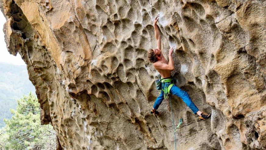 In überhängender Kalksteinwand hängt Bergführer Florian Storkenmaier mit blauer Hose und Klettergurt.
