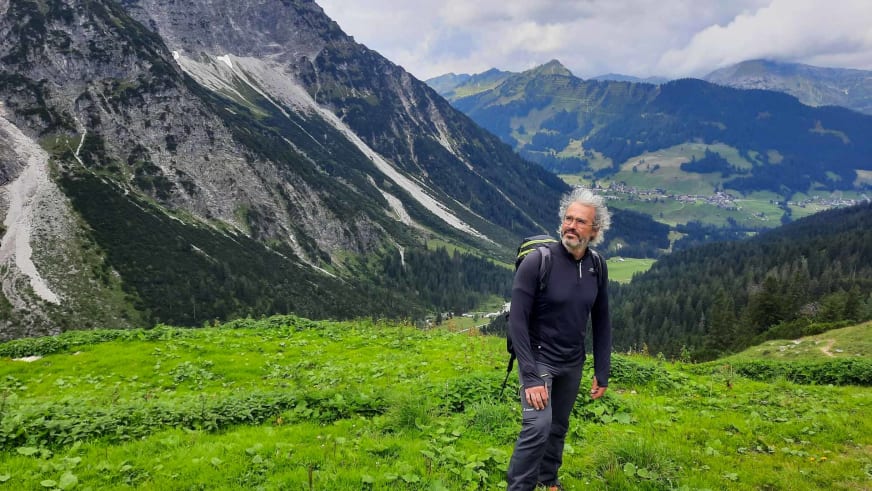 Auf grüner Almwiese in den Picos de Europa steht Bergwanderführer Nacho Carreras Codina mit Rucksack.
