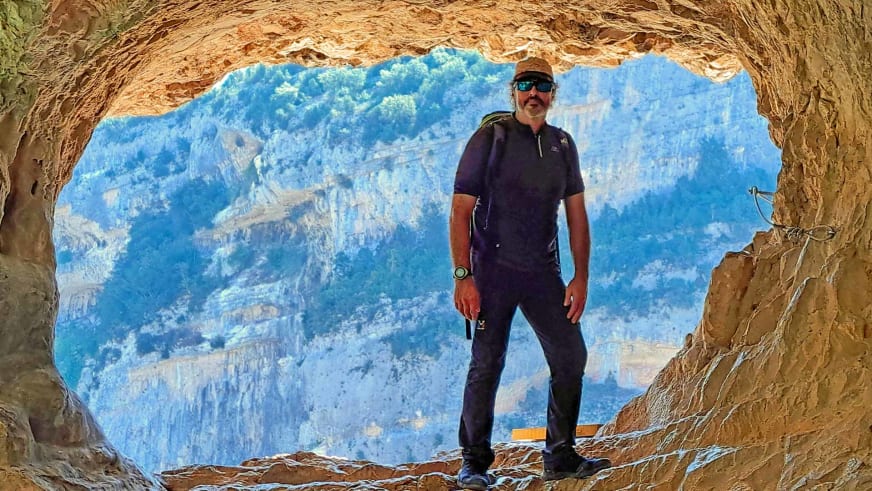 Bergwanderführer Nacho Carreras Codina steht in natürlicher Felshöhle mit Blick auf Berglandschaft der Picos de Europa.