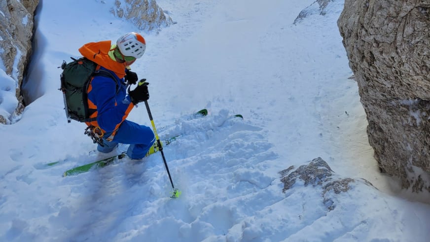 Bergführer Tobias Kostenbader fährt mit grünen Skiern durch tiefen Pulverschnee in einer engen Felsrinne.