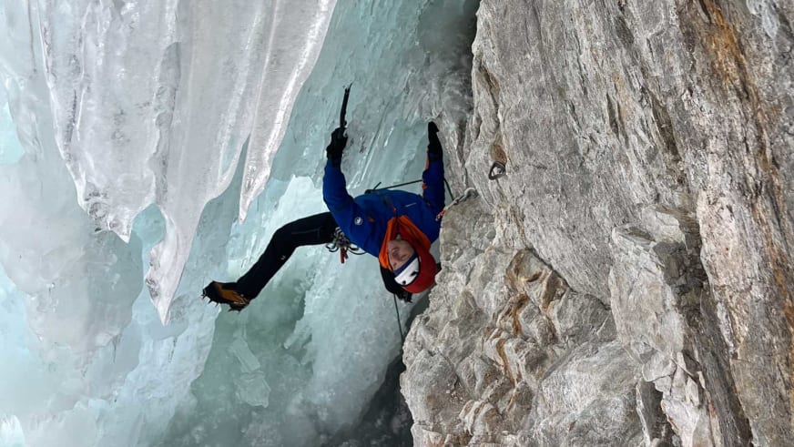 Bergführer Tobias Kostenbader klettert mit Eisgeräten und Steigeisen an einer steilen hellblauen Eiswand.