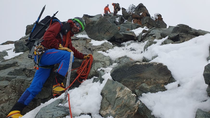 Bergwanderführer Karsten Clauß führt mit Steigeisen und Seil eine Hochtour an steiler schneebedeckter Felswand.