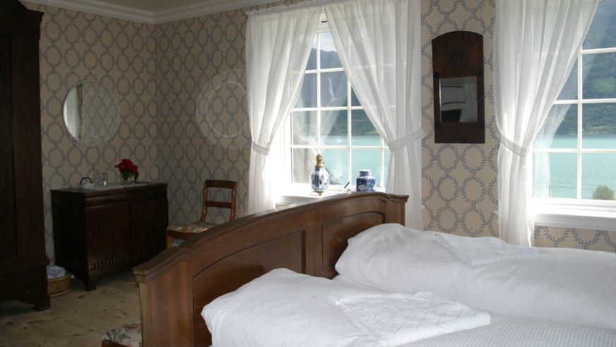 Traditionell eingerichtetes Doppelzimmer im Nes Gard mit Holzbett und direktem Blick auf den Fjord.