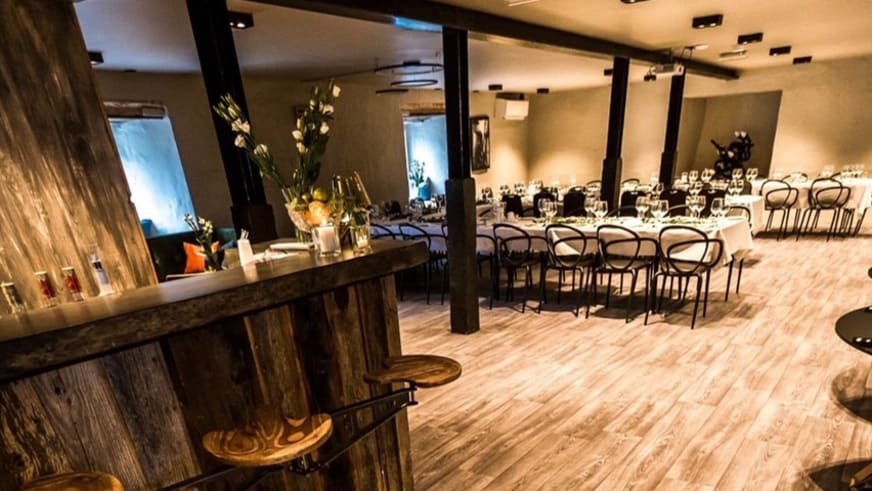 Moderne Bar aus Holz im Restaurant des Nes Gard mit Barhockern und industriellem Design.