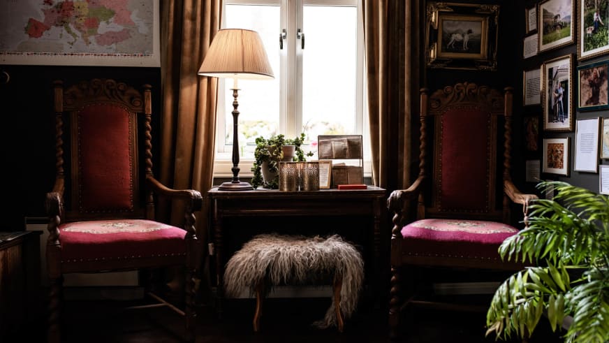 Traditionell eingerichtetes Zimmer im Fjærland Fjordstove Hotell mit antiken Holzstühlen und rotem Lederbezug.