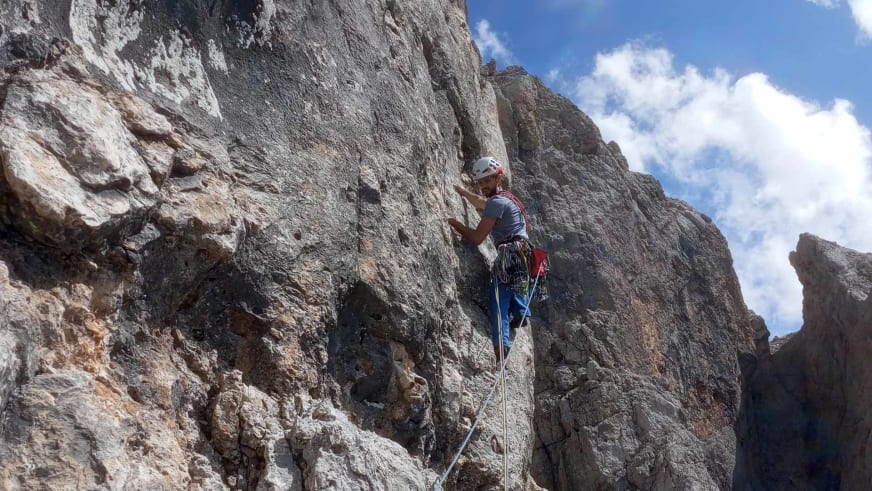 Im freien Vorstieg klettert Bergführer Cesare Lotti an steiler Kalksteinwand mit Seil.