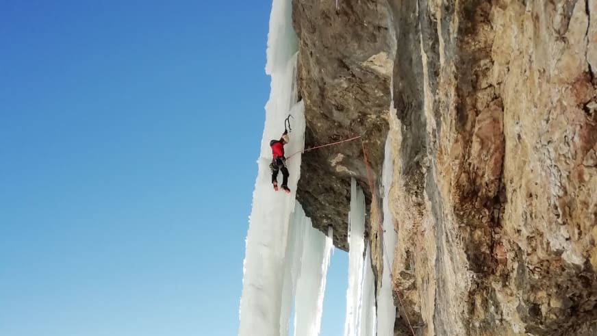 Mit Eisgeräten und Steigeisen klettert Bergführer Cesare Lotti an steiler blauer Eiswand.
