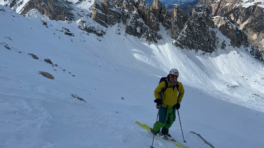 Bergwanderführer Patrick Hindelang auf gelben Skiern in steilem Schneegelände vor hoher Felswand.