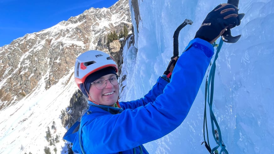 Bergführer Franz Brodkorb trägt weißen Kletterhelm und blaue Winterjacke, hält einen Eispickel und lächelt in die Kamera.
