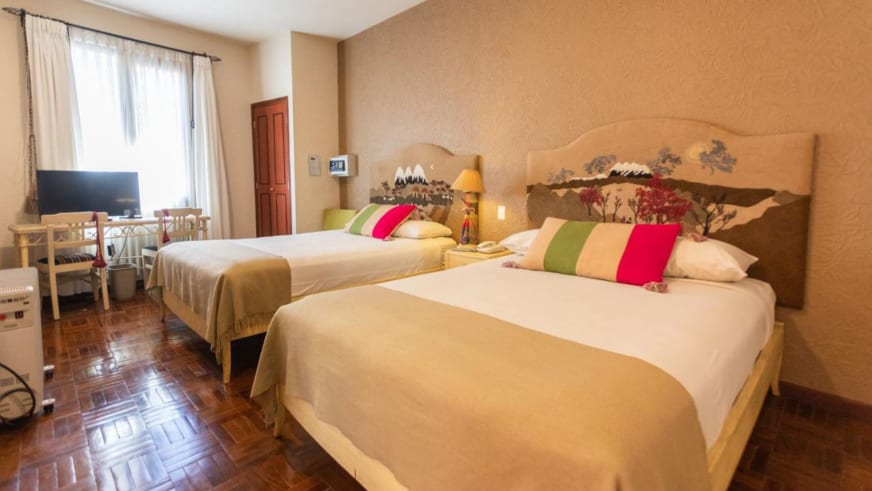 Hotelzimmer mit zwei Betten und Berglandschafts-Wandmalerei im Hotel Rosario La Paz.