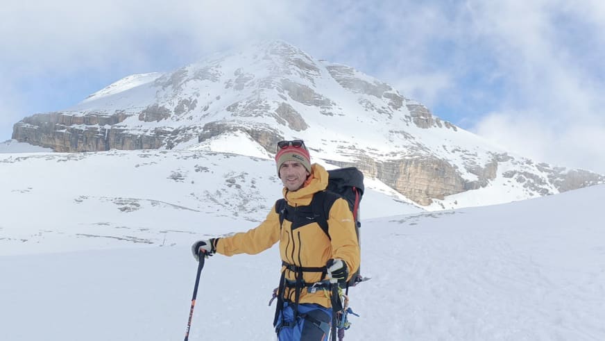 In gelber Winterjacke und mit Skistock steht Bergführerin Luca Trubbiani lächelnd auf verschneiter Fläche.
