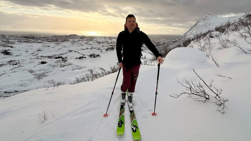 Wolfgang Pusch als Bergführer steht mit grünen Tourenski und roten Skistöcken in verschneiter Berglandschaft.