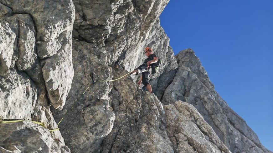 Bergführer Wolfgang Pusch seilt sich mit gelbem Seil und rotem Helm an einer steilen Kalksteinwand ab.