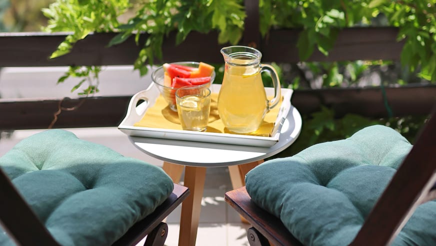 Balkon des Hotel Rajna Paklenica mit Holzstühlen, rundem Tisch und Erfrischungen.