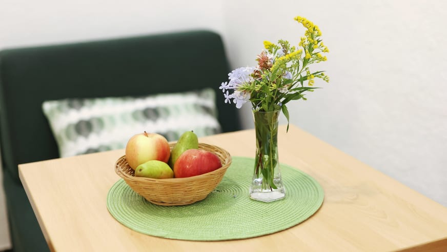 Holztisch mit Früchtekorb und Blumenvase in einem Zimmer des Hotel Rajna Paklenica.
