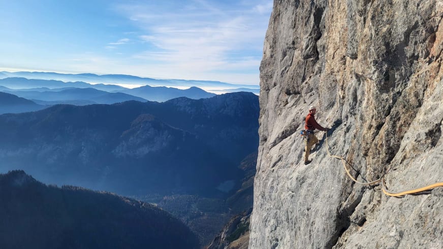 Bergführer Christoph Blumrich klettert in roter Jacke an steiler Kalksteinwand mit gelbem Kletterseil.
