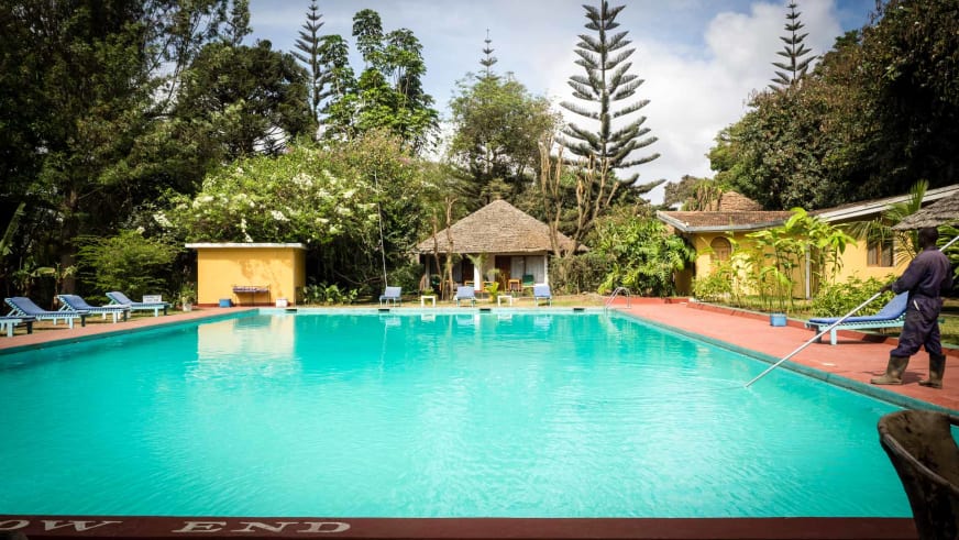 Poolpflege am türkisblauen Swimmingpool der Ilboru Safari Lodge in tropischer Umgebung.