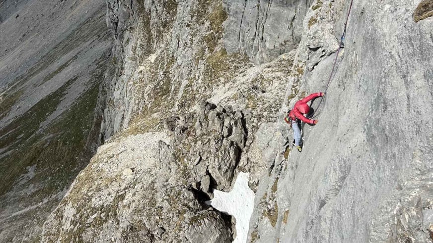 Bergführerin Monika Hümmer in roter Jacke klettert an steiler Kalksteinwand mit Seil.